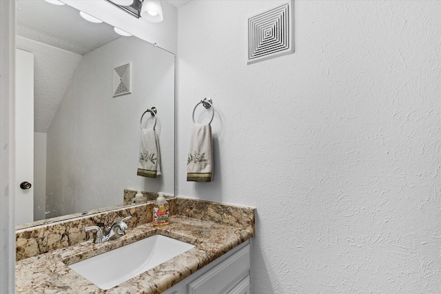 bathroom featuring lofted ceiling and vanity