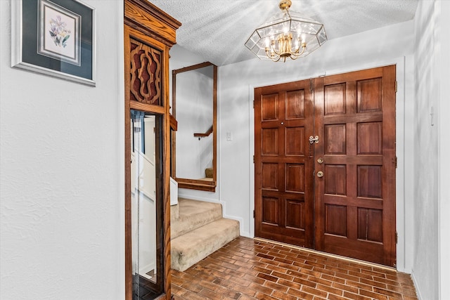 entryway with a chandelier and a textured ceiling