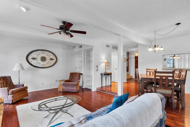 living room featuring ceiling fan with notable chandelier, dark hardwood / wood-style floors, and a textured ceiling