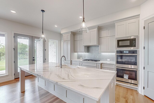 kitchen featuring sink, an island with sink, white cabinetry, a fireplace, and stainless steel appliances