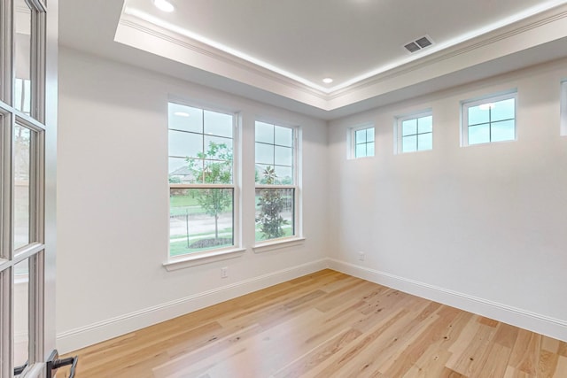 spare room with light hardwood / wood-style flooring, crown molding, and a tray ceiling