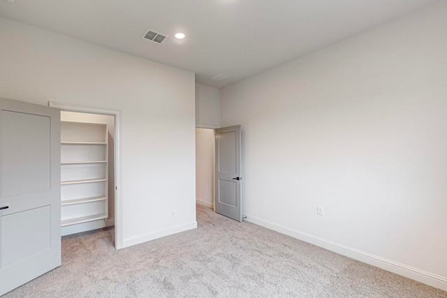 unfurnished bedroom with a spacious closet, light colored carpet, and a closet