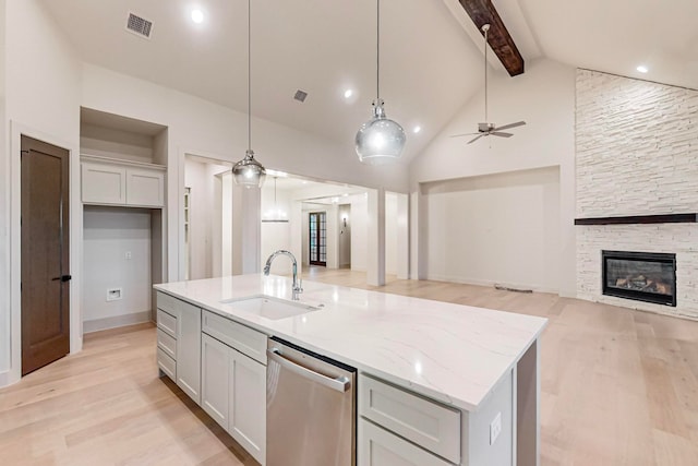 kitchen with hanging light fixtures, a stone fireplace, dishwasher, ceiling fan, and sink