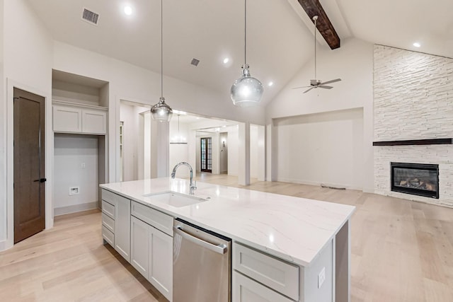 kitchen with dishwasher, open floor plan, a kitchen island with sink, pendant lighting, and a sink