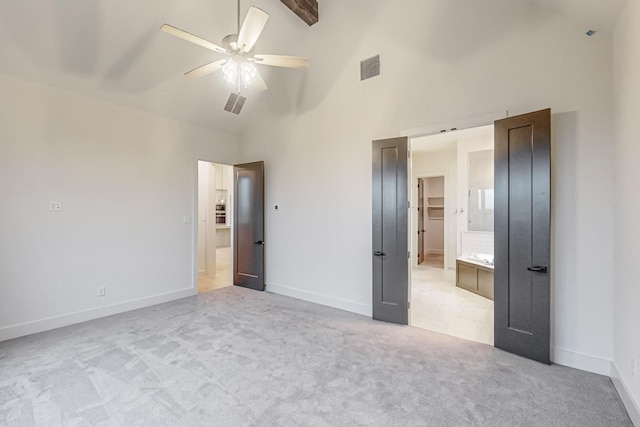 unfurnished bedroom featuring baseboards, visible vents, connected bathroom, light colored carpet, and high vaulted ceiling