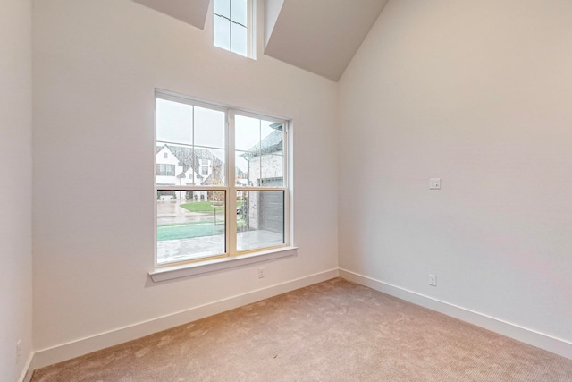 carpeted empty room with high vaulted ceiling