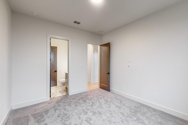 unfurnished bedroom with baseboards, connected bathroom, visible vents, and light colored carpet