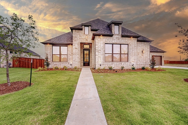 view of front of home with a front yard, an attached garage, brick siding, and roof with shingles