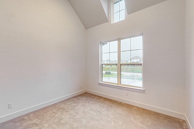 empty room featuring baseboards, high vaulted ceiling, and light colored carpet