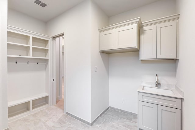 washroom with visible vents, a sink, and baseboards