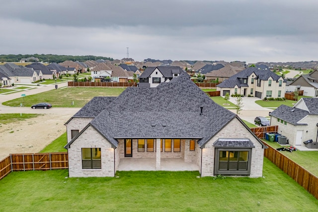 back of house with a shingled roof, a residential view, and a fenced backyard