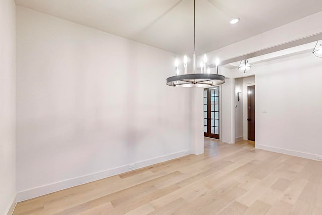 empty room with wood-type flooring and an inviting chandelier