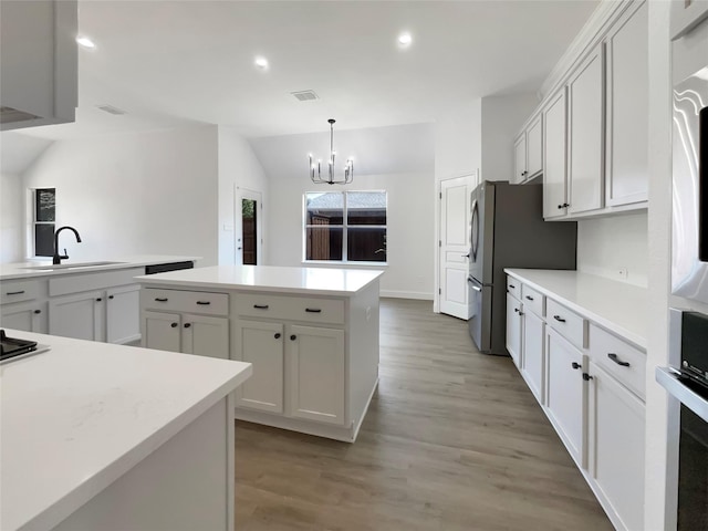 kitchen with vaulted ceiling, light countertops, a sink, and a center island