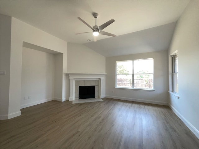 unfurnished living room with baseboards, a tile fireplace, ceiling fan, wood finished floors, and vaulted ceiling