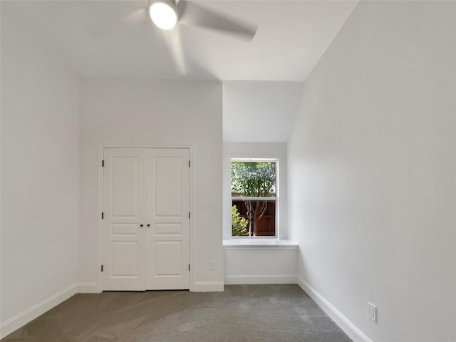 carpeted empty room featuring lofted ceiling, ceiling fan, and baseboards