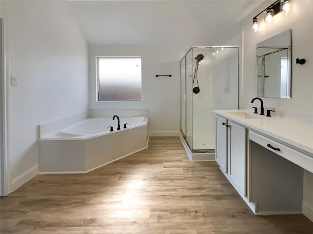 bathroom featuring a garden tub, a stall shower, vanity, wood finished floors, and baseboards