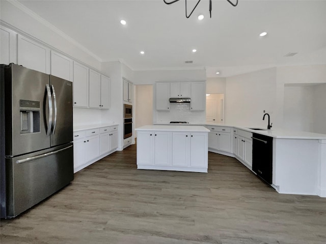 kitchen with a kitchen island, a sink, ornamental molding, appliances with stainless steel finishes, and light wood-type flooring