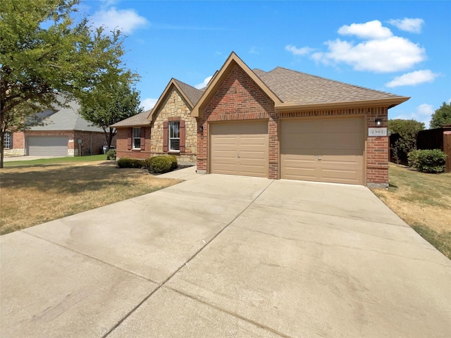 view of front of property featuring brick siding, roof with shingles, an attached garage, stone siding, and driveway