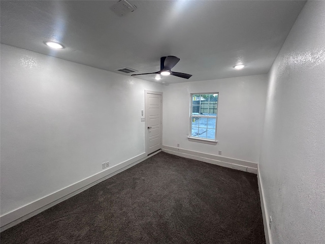 empty room featuring ceiling fan and dark colored carpet