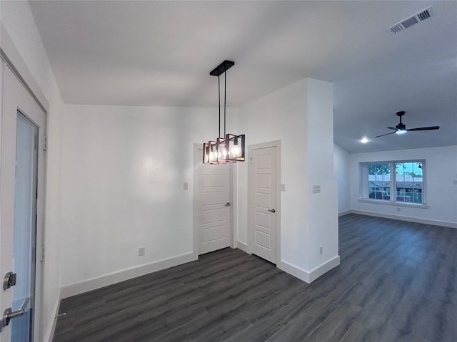 unfurnished dining area with dark wood-type flooring and ceiling fan with notable chandelier