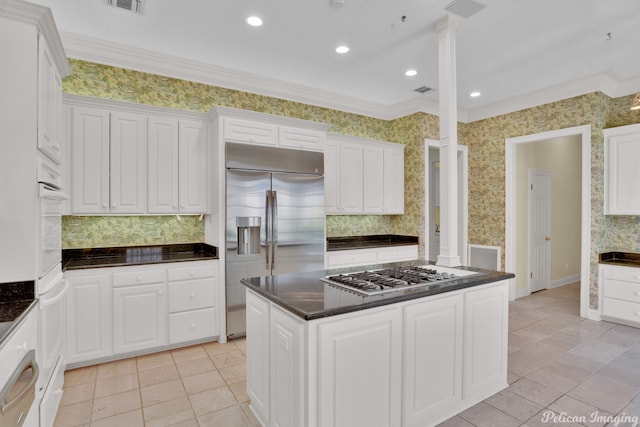 kitchen with appliances with stainless steel finishes, a center island, tasteful backsplash, and light tile patterned flooring