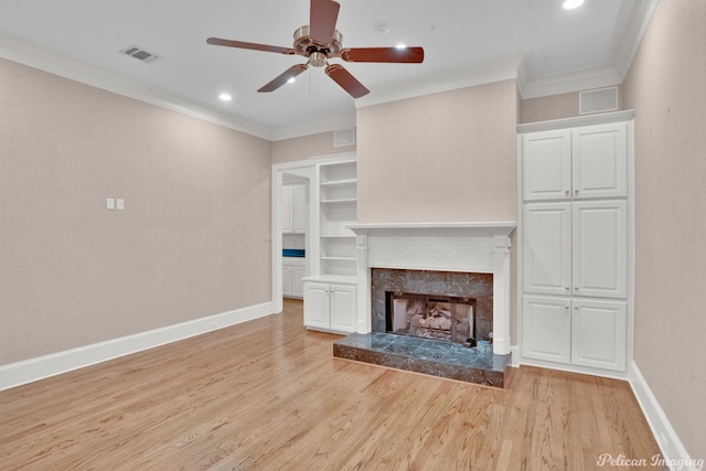 unfurnished living room with light wood-type flooring, ornamental molding, a high end fireplace, and ceiling fan