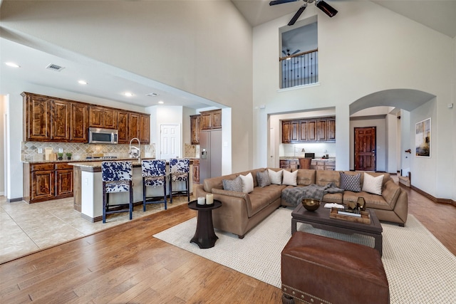 living room with baseboards, visible vents, arched walkways, light wood-style floors, and recessed lighting