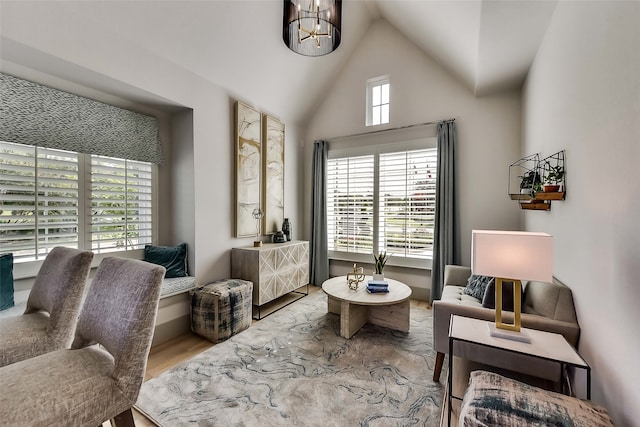 living area with hardwood / wood-style flooring, vaulted ceiling, and a notable chandelier