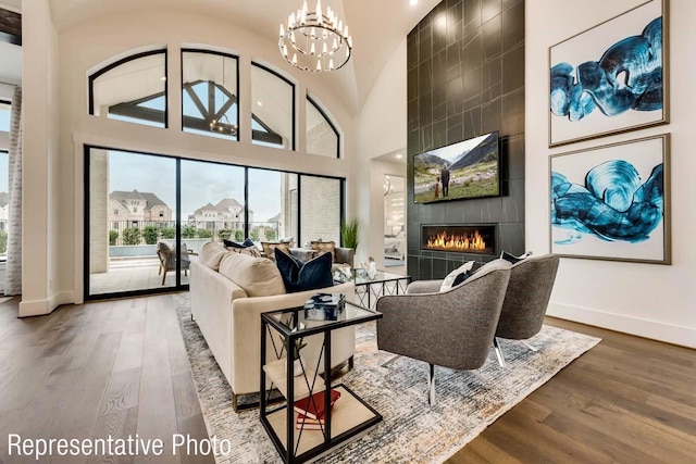 living room with a fireplace, wood-type flooring, a high ceiling, and a notable chandelier