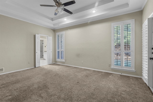 carpeted empty room featuring ceiling fan, a raised ceiling, and crown molding