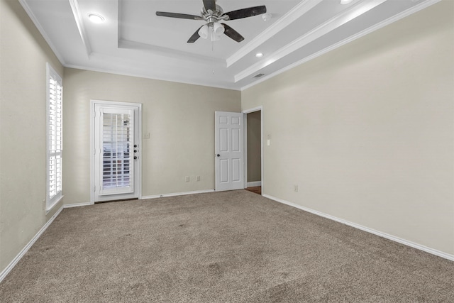 carpeted spare room with a tray ceiling, ornamental molding, and ceiling fan