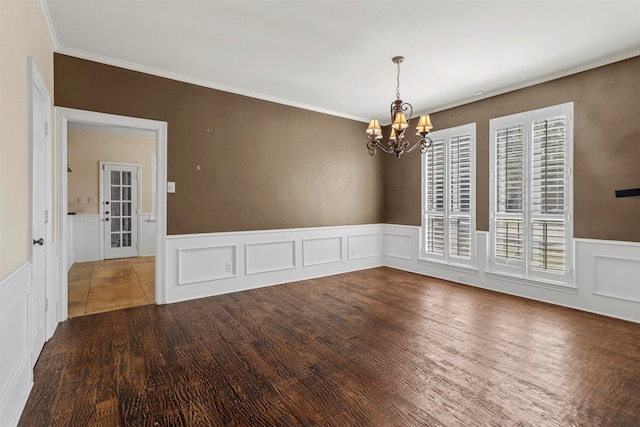 empty room with crown molding, wood-type flooring, and a chandelier