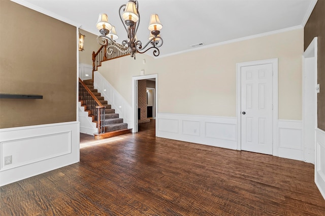 unfurnished living room featuring crown molding, dark hardwood / wood-style floors, and an inviting chandelier