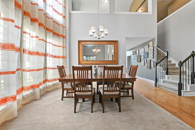 dining space with a chandelier, wood-type flooring, and high vaulted ceiling