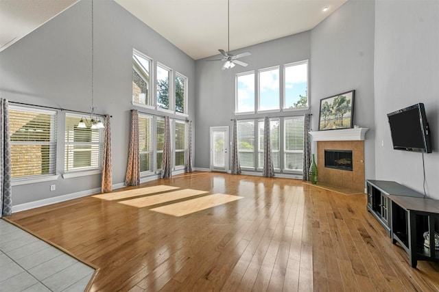 unfurnished living room featuring a wealth of natural light, a fireplace, a towering ceiling, and light hardwood / wood-style floors