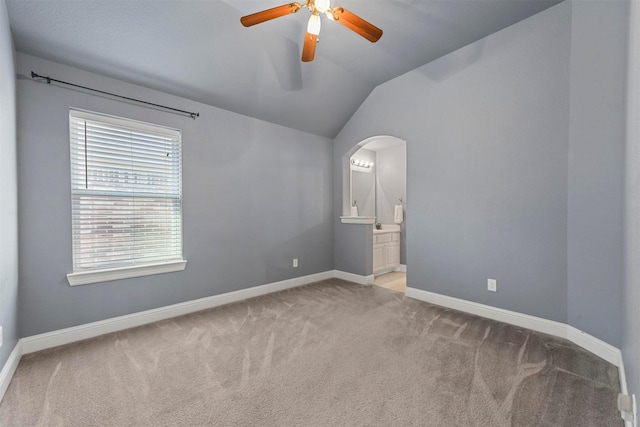 carpeted empty room featuring vaulted ceiling and ceiling fan