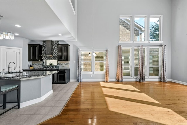 kitchen featuring wall chimney range hood, light hardwood / wood-style flooring, a wealth of natural light, and sink