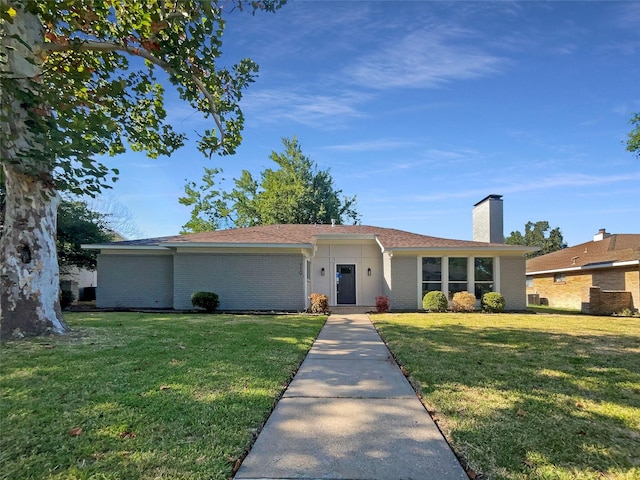 single story home with a front lawn, a chimney, and brick siding