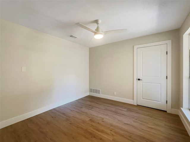 spare room featuring ceiling fan, wood finished floors, visible vents, and baseboards