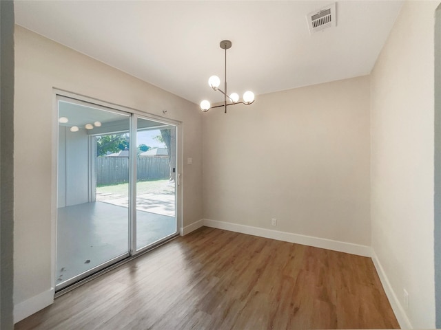 empty room with light wood-style flooring, visible vents, a chandelier, and baseboards