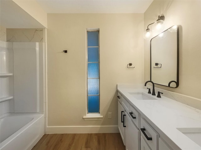 full bathroom featuring double vanity, shower / bath combination, a sink, wood finished floors, and baseboards