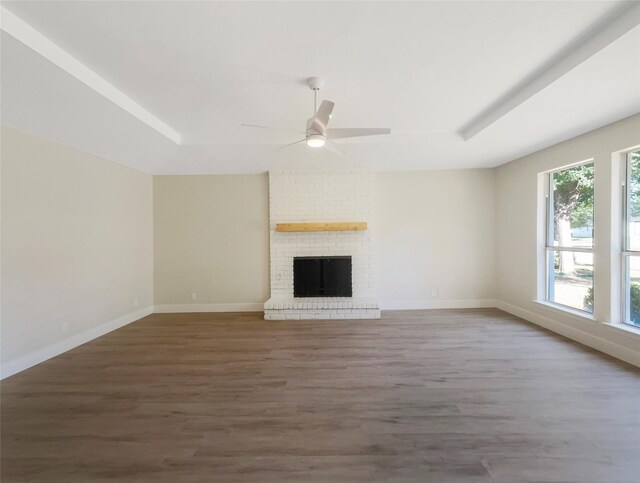 unfurnished living room with brick wall, ceiling fan, hardwood / wood-style floors, and a brick fireplace