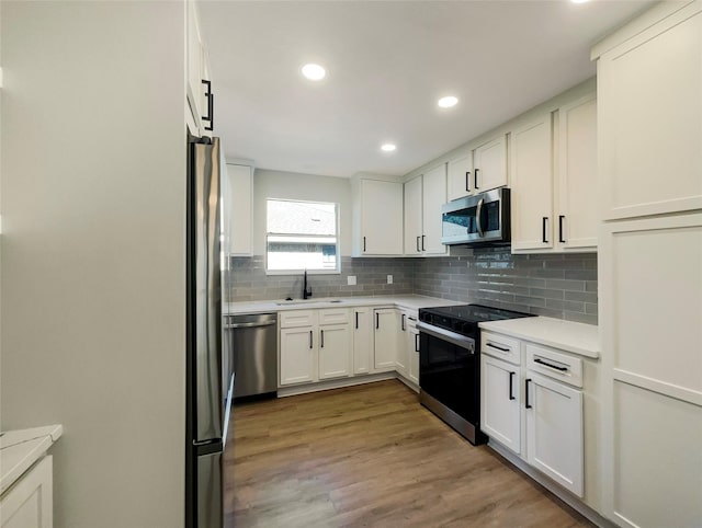 kitchen featuring decorative backsplash, appliances with stainless steel finishes, light countertops, white cabinetry, and a sink