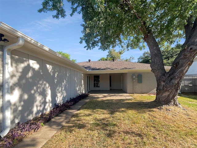 exterior space with brick siding, a lawn, and fence