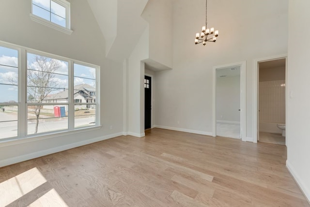 1029 Bleriot Dr, Fate, TX 75087 - empty room featuring a towering ceiling, a chandelier, and light wood finished floors