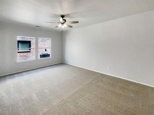 empty room featuring carpet floors, visible vents, ornamental molding, ceiling fan, and baseboards