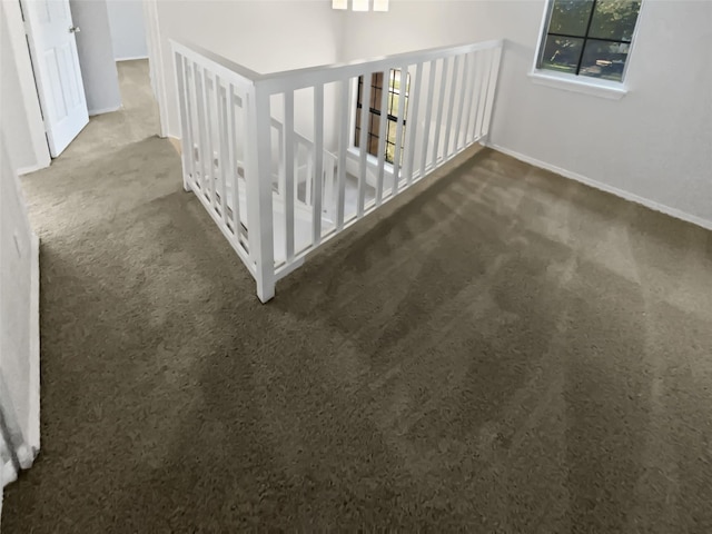 hall with dark colored carpet and baseboards