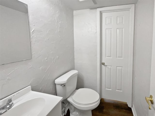 half bath featuring vanity, toilet, and wood finished floors