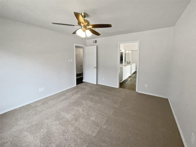 unfurnished bedroom with ceiling fan, visible vents, baseboards, dark carpet, and ensuite bath