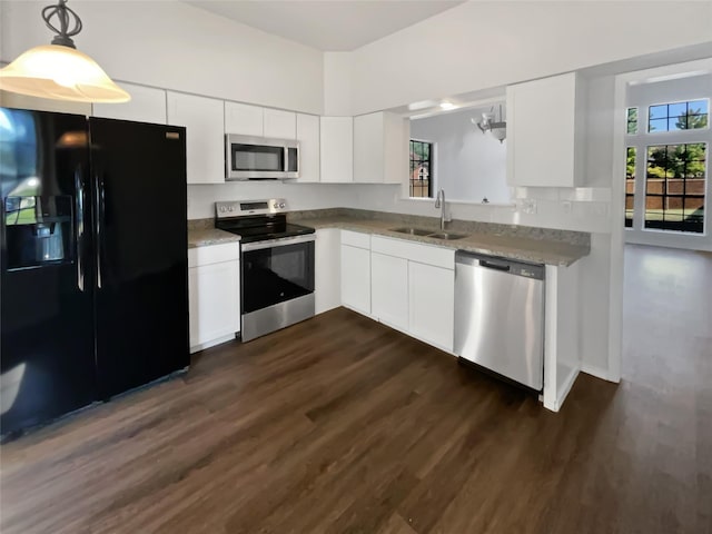 kitchen with appliances with stainless steel finishes, dark wood finished floors, white cabinetry, and a sink